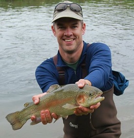 Daniel Vimont holding a rainbow trout while standing in Big Green River